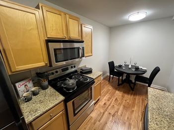 A kitchen and dining room with wood flooring and stainless steel appliances